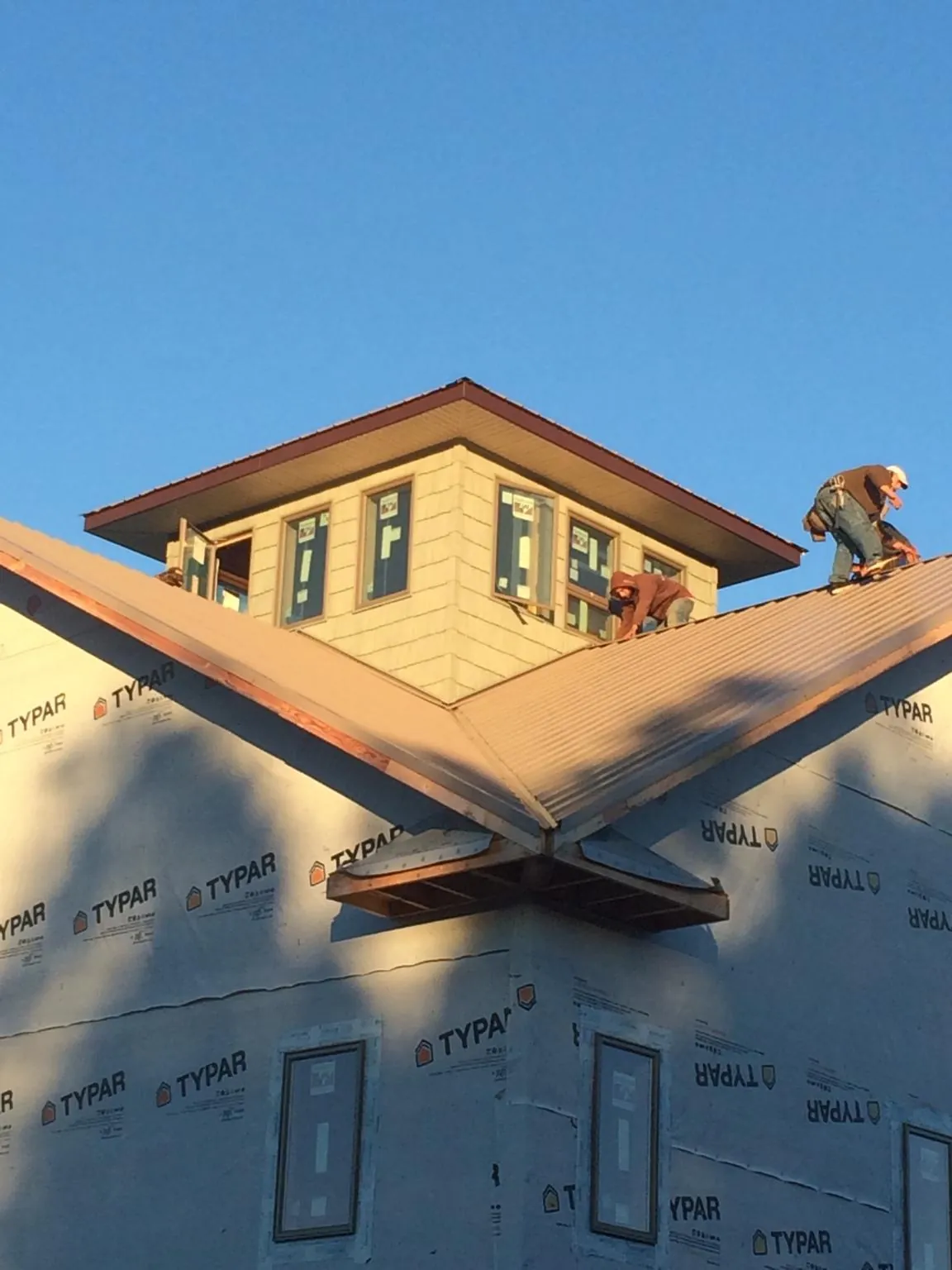 Roofers working around a rooftop cupola on a new metal roof at sunset — Roof Waterproofing in Mc Intosh by Roofing Brothers